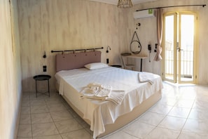 A hotel room with a large bed, a small bedside table, a chair, a desk, and a window with curtains. - Argassi Beach Hotel (Zakynthos)