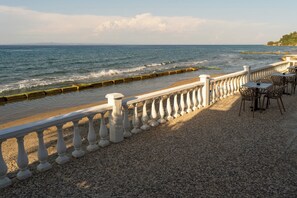A seaside terrace with a railing, tables, and chairs. - Argassi Beach Hotel (Zakynthos)