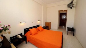 A bedroom with a bed, bedside tables, a nightstand, a small table with a vase of flowers, and a television mounted on the wall.