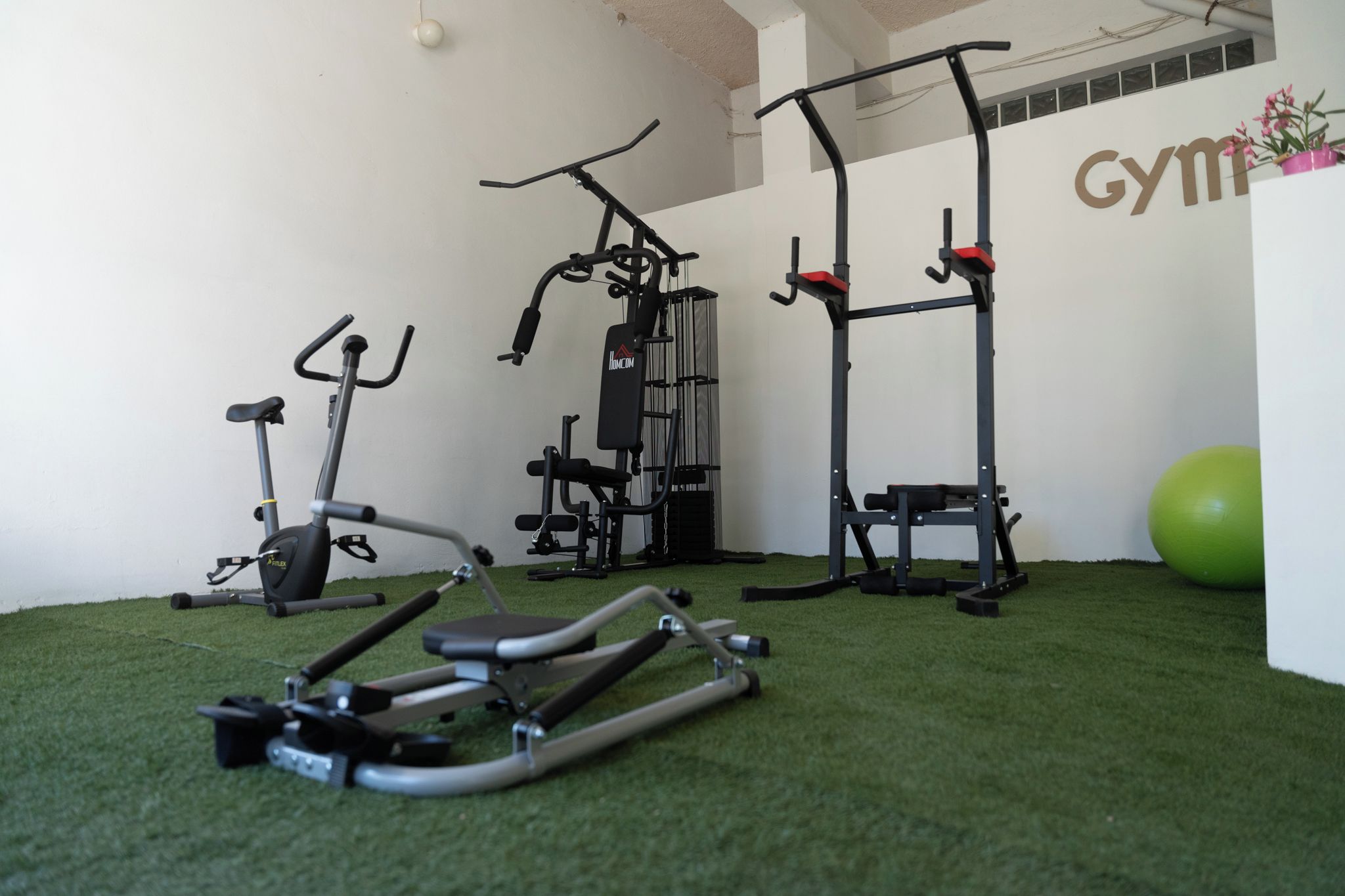 A gym with exercise equipment including a stationary bike, elliptical, and a pull-up bar.