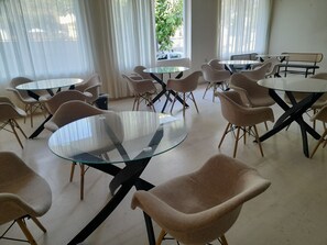 A modern interior with round glass tables and beige chairs arranged around them. - Argassi Beach Hotel (Zakynthos)