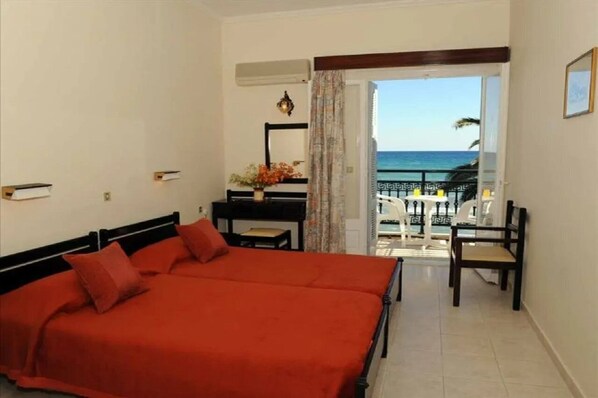 A hotel room with a bed, a desk, a chair, and a view of the sea. - Argassi Beach Hotel (Zakynthos)