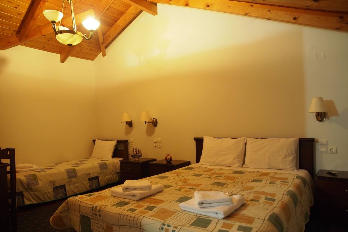 Een hotelkamer met twee bedden, een houten plafond en een decoratie van een schip op het nachtkastje.