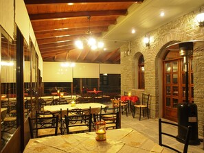 A restaurant with wooden beams, stone walls, and tables with candles.