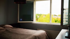 A bedroom with a large window, a bed, and a radiator. - Central - 2 Bedroom Apartment (Sollentuna)