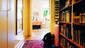 A hallway with a bookshelf, a dining area, and a door leading to another room.