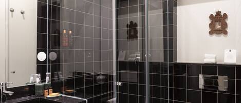 Une salle de bain moderne avec une douche à parois de verre, un lavabo en marbre noir et des toilettes blanches.