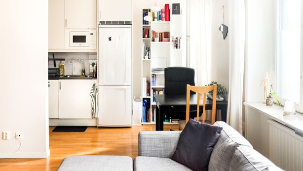 Un salon moderne avec un canapé gris, une chaise en bois et une bibliothèque remplie de livres.