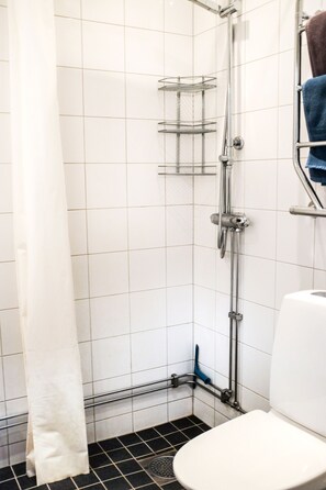 A bathroom with a shower, toilet, and a towel rack. - Comfortable Studio Apartment - Midsommarkransen (Hägersten)