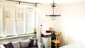 Une pièce comprenant un canapé, un bureau avec des tiroirs, une chaise, un lit et un lustre.