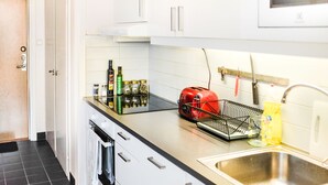 Une cuisine moderne avec des meubles blancs, un évier en acier inoxydable et un grille-pain rouge.