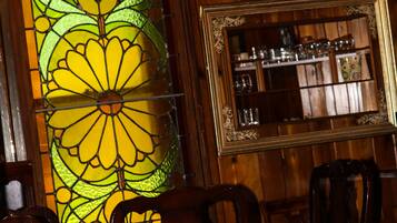 A dining area with wooden paneling, a stained glass window, a chandelier, and a mirror with a wooden frame.