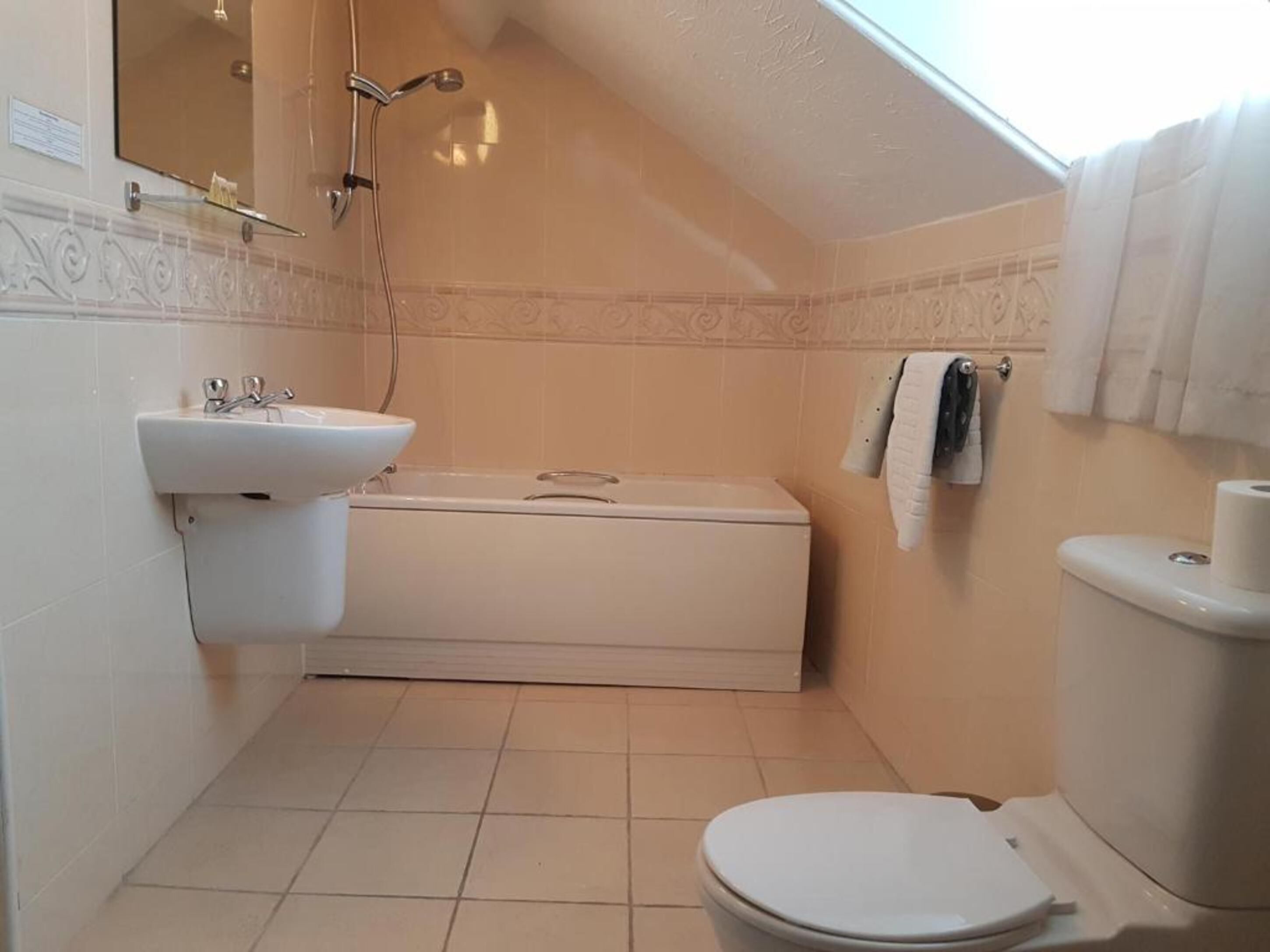 A small, compact bathroom with a toilet, sink, and shower.