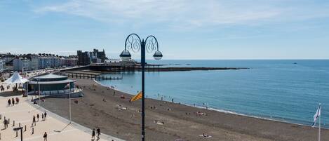 Un paseo marítimo costero con playa, paseo y muelle.