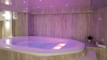 A modern spa area with a hot tub, wooden walls, and a small potted plant.