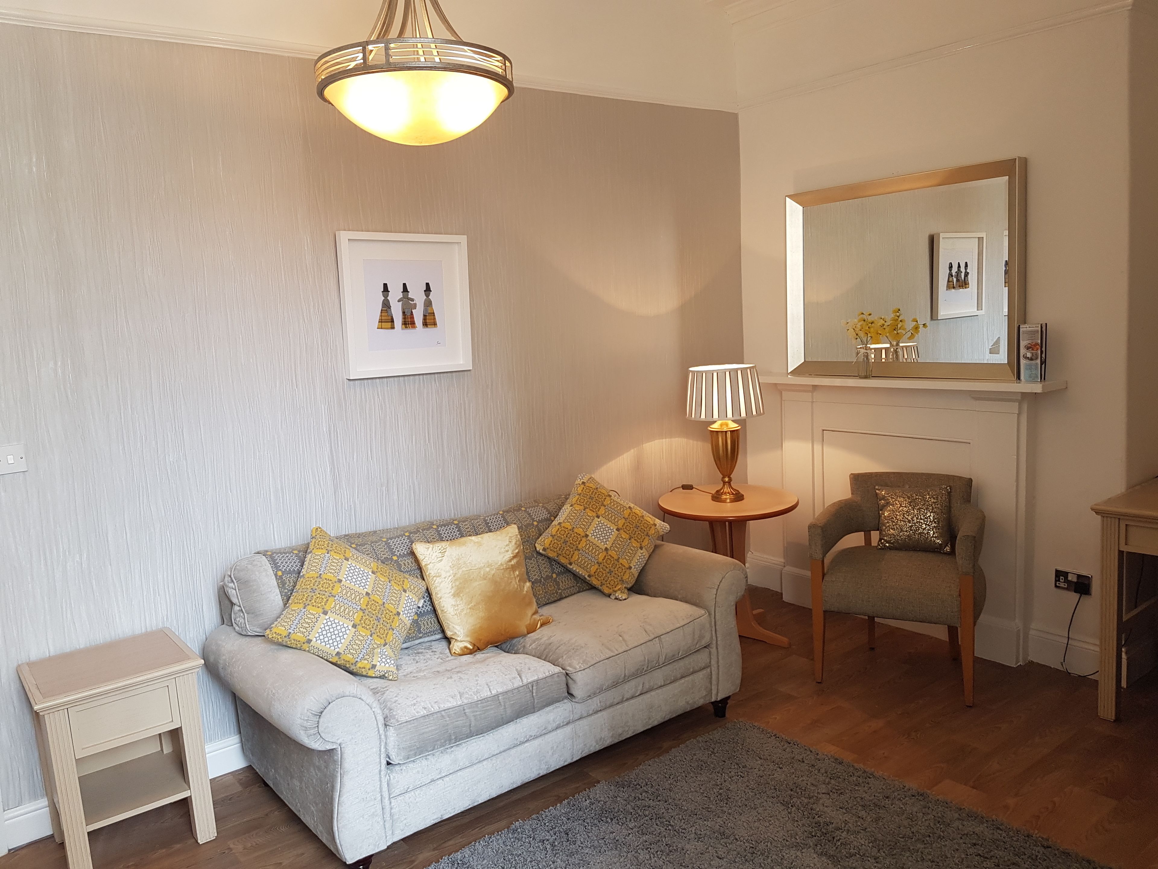 A living room with a sofa, armchair, small side table, and a lamp.