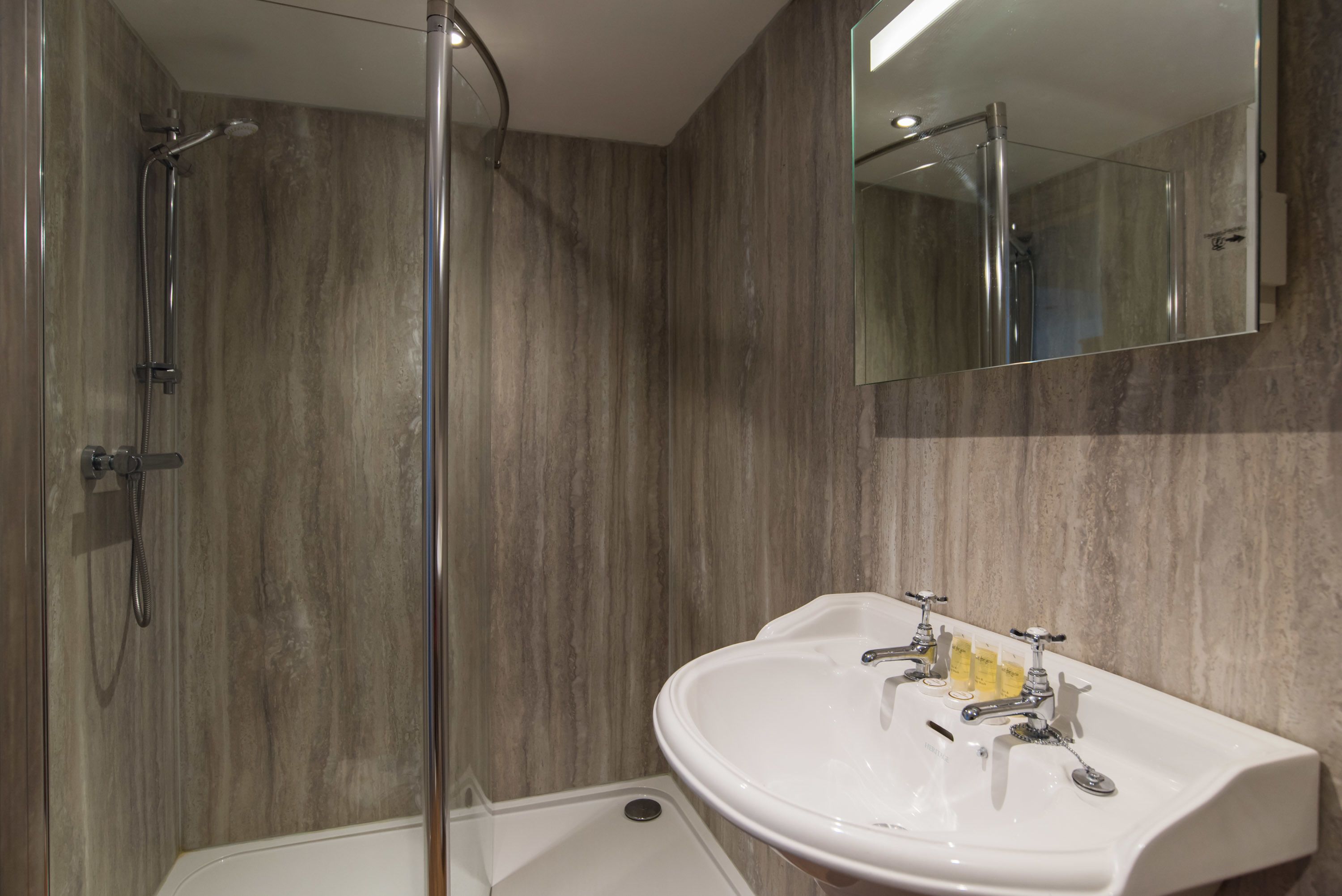 Un baño moderno con ducha, lavabo y espejo.