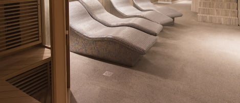 A spa area with reclining chairs, a massage table, and a large bathtub.