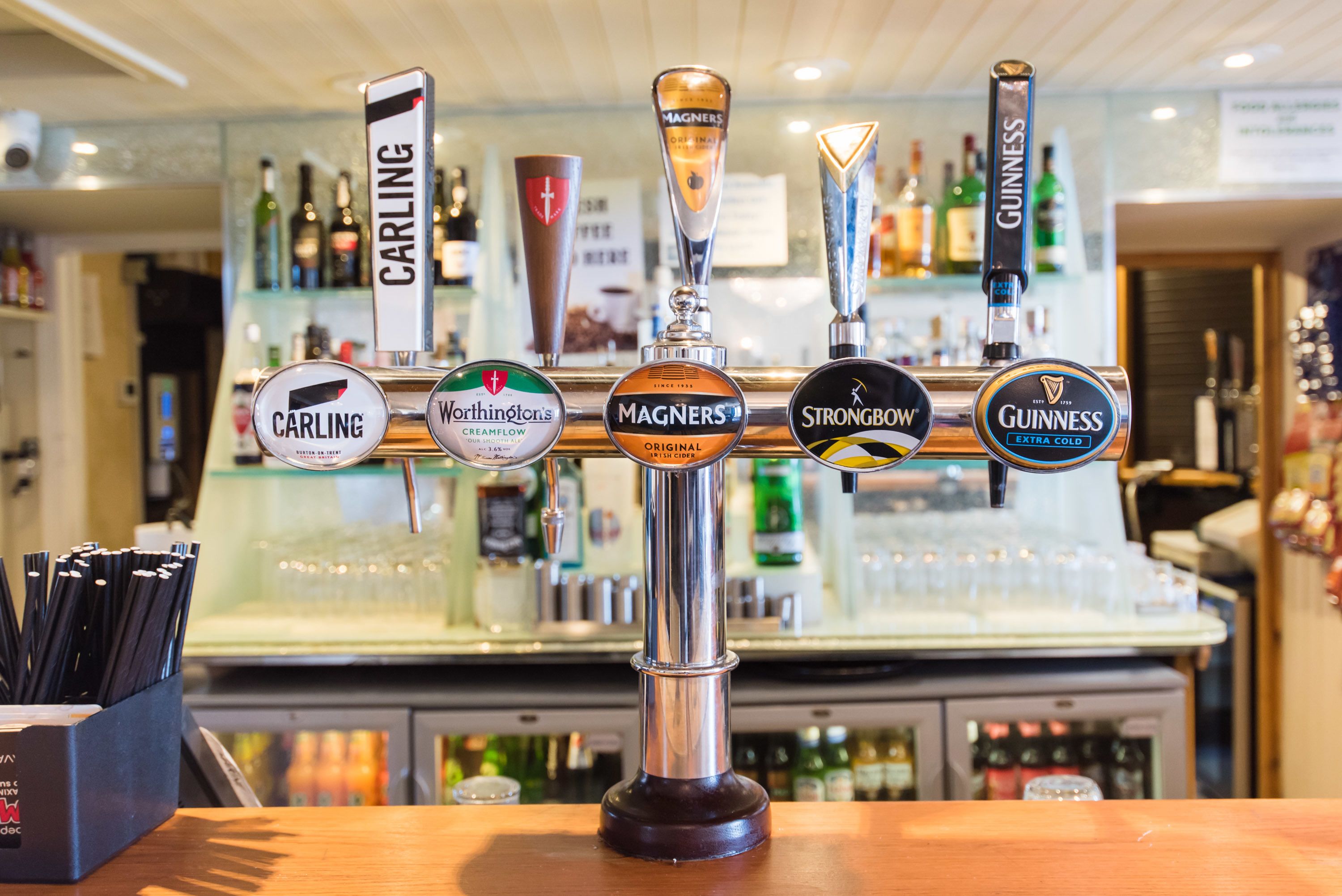 A bar with multiple beer taps including brands like Carling, Worthington's, Magners, Strongbow, and Guinness.