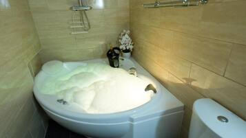 Un baño con una bañera grande, un inodoro y una zona de ducha.