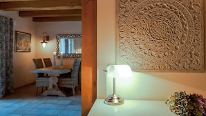 Un comedor con una mesa de madera, sillas de mimbre y un panel decorativo en la pared.