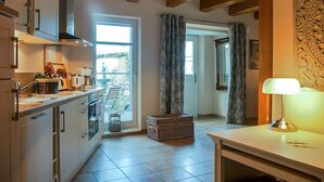 Una cocina moderna con armarios blancos, horno empotrado y ventana con vistas a un balcón.