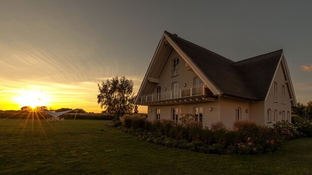A large, single-story house with a steeply pitched roof and a balcony on the second floor. - Lerchenhof Reestow (Rankwitz)