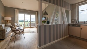 A modern kitchen with striped walls, a dining area with wicker furniture, and a view through a glass door to an outdoor patio. - Lerchenhof Reestow (Rankwitz)