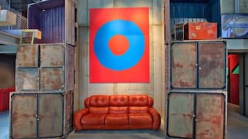 Una habitación con una obra de arte circular grande, en rojo y azul, en la pared, un sofá de cuero marrón y unidades de almacenamiento metálicas.