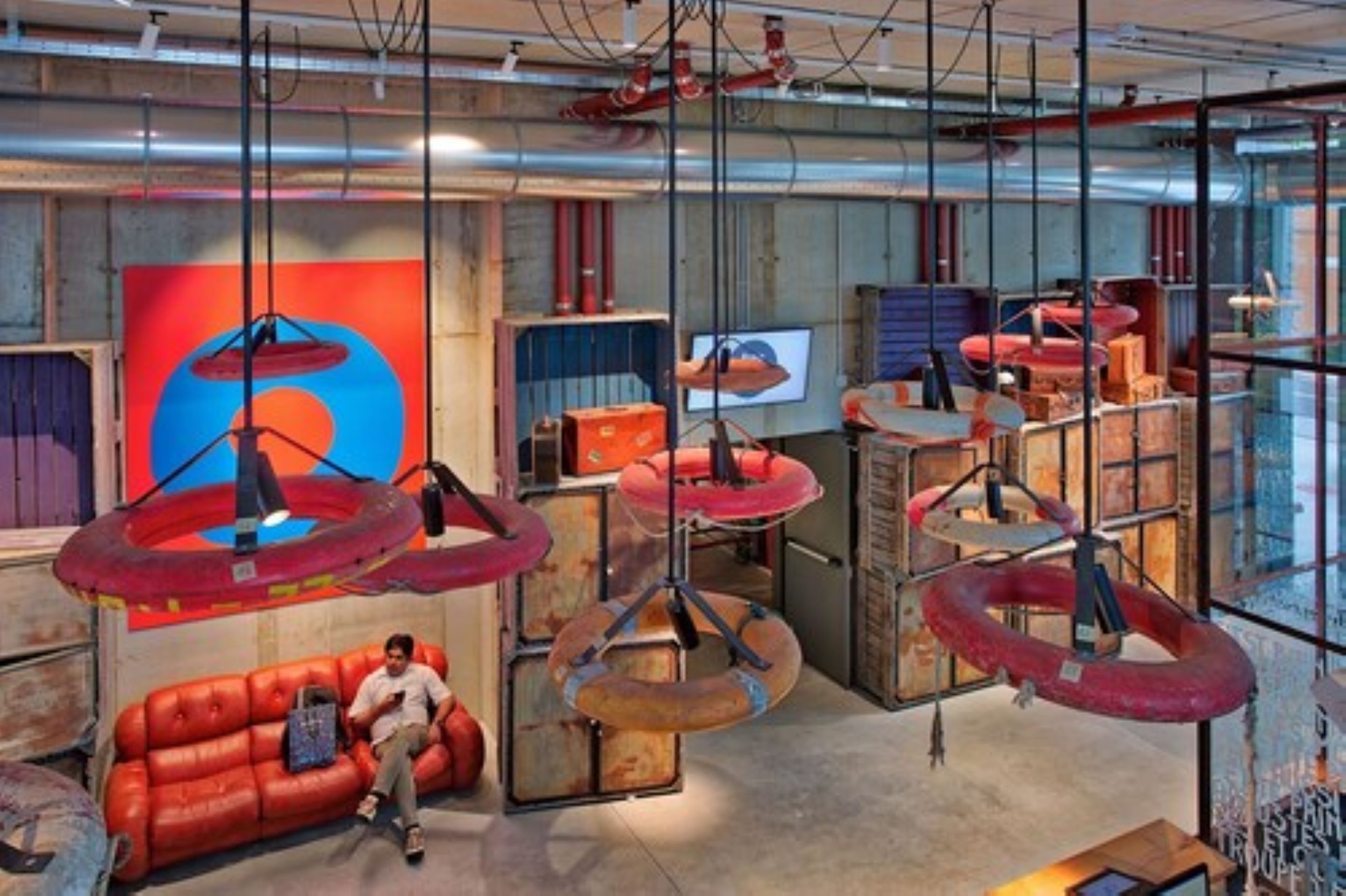 A modern interior with a red sofa, hanging circular structures, and a large abstract painting on the wall.