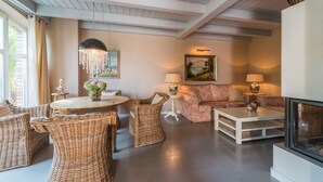 A cozy living room with wicker furniture, a fireplace, and artwork on the walls. - Bauernkate Liepe (Rankwitz)