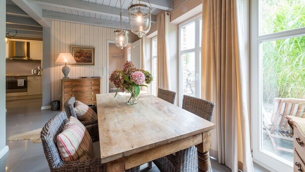 A dining area with a wooden table, wicker chairs, and a vase of flowers. - Bauernkate Liepe (Rankwitz)