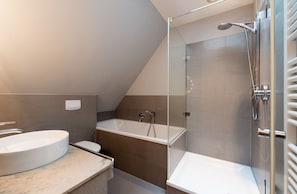 Un baño moderno con una bañera independiente, una ducha con cerramiento de vidrio y un lavamanos grande.