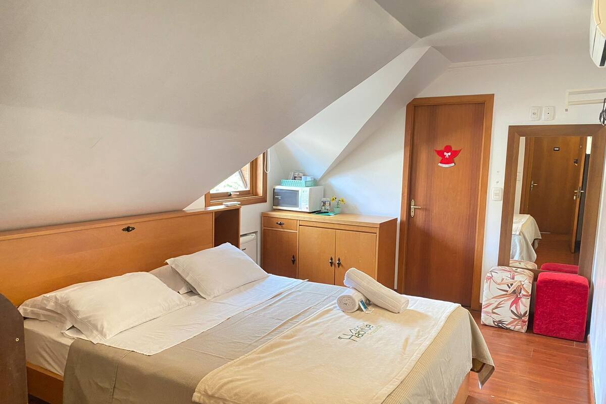 A bedroom with a bed, wooden wardrobe, and a small kitchenette.