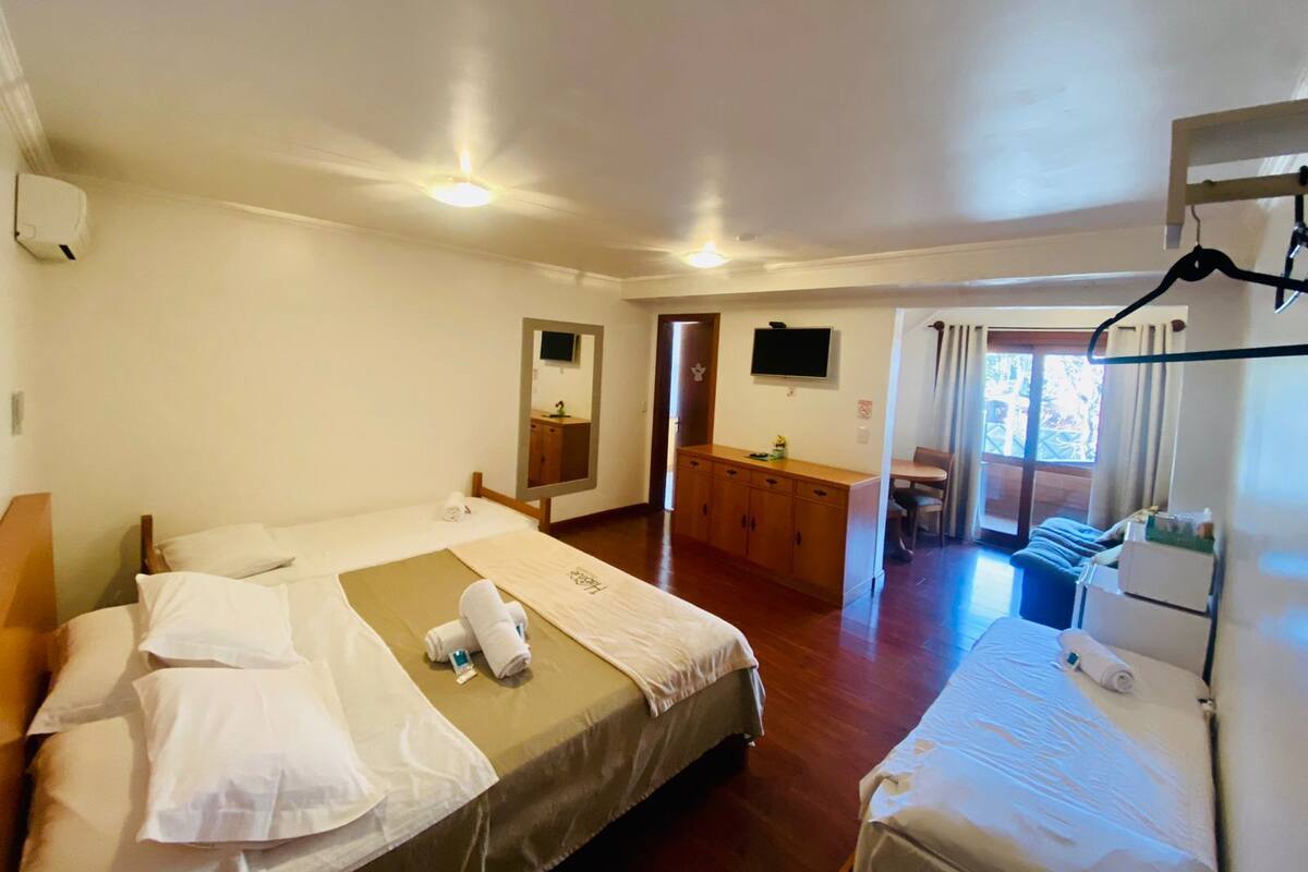 A hotel room with two beds, a bathroom, and a TV.