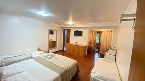 A hotel room with two single beds, a wooden dresser, a television, and a dining area with a table and chairs. - Pousada Habitue (Gramado)