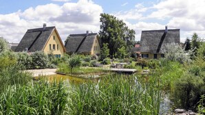 A row of traditional houses with thatched roofs, a pond, and lush greenery. - Reetdachhaus in Krienke (Rankwitz)