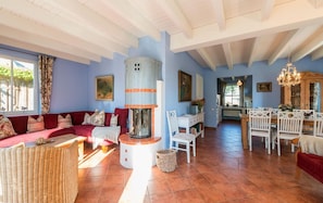 A spacious living room with a red sofa, a fireplace, and a dining area with white furniture. - Reetdachhaus in Krienke (Rankwitz)