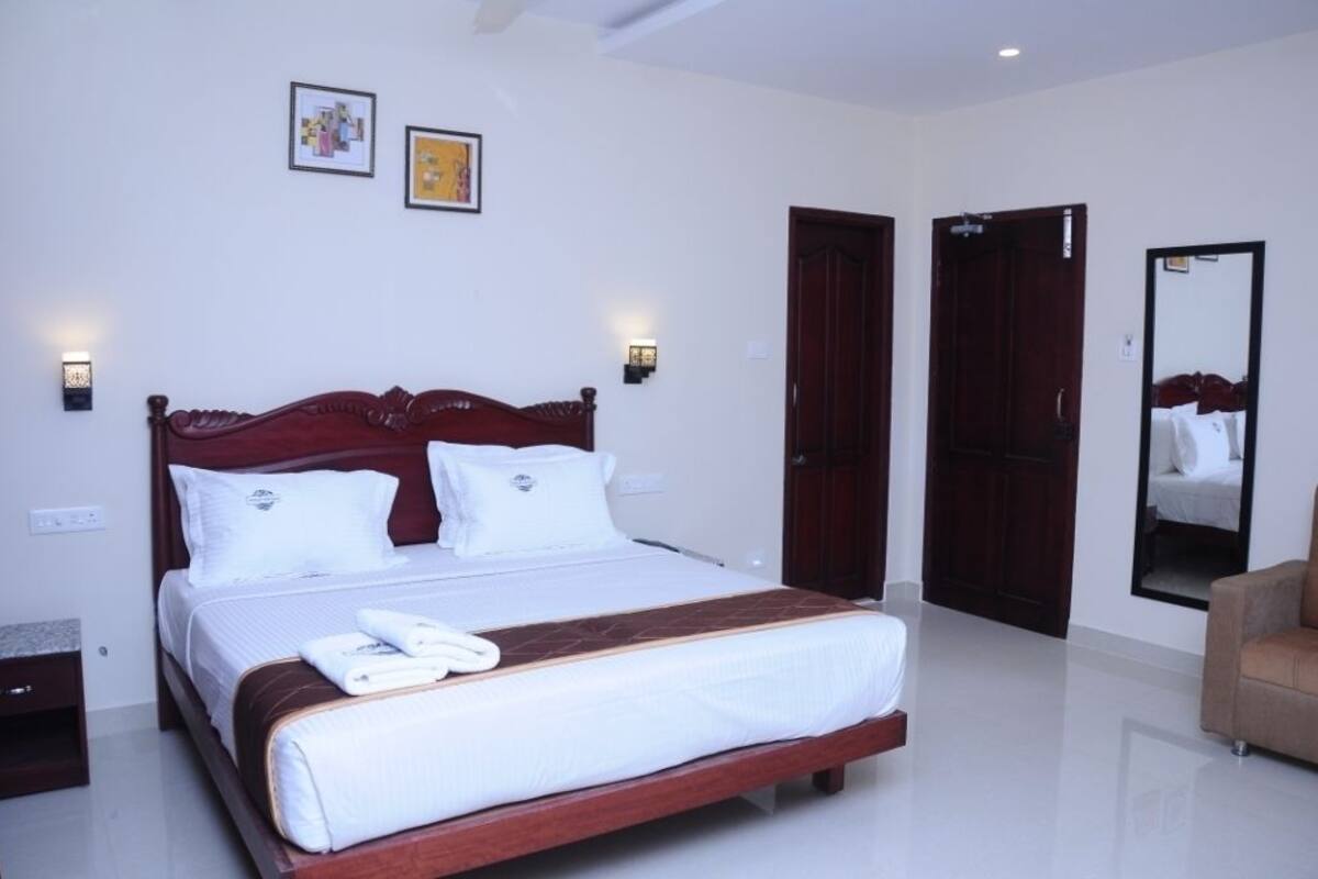 Ein Hotelzimmer mit einem großen Bett, zwei Nachttischlampen, einem Holzkopfschild, einem Spiegel und einer Tür.