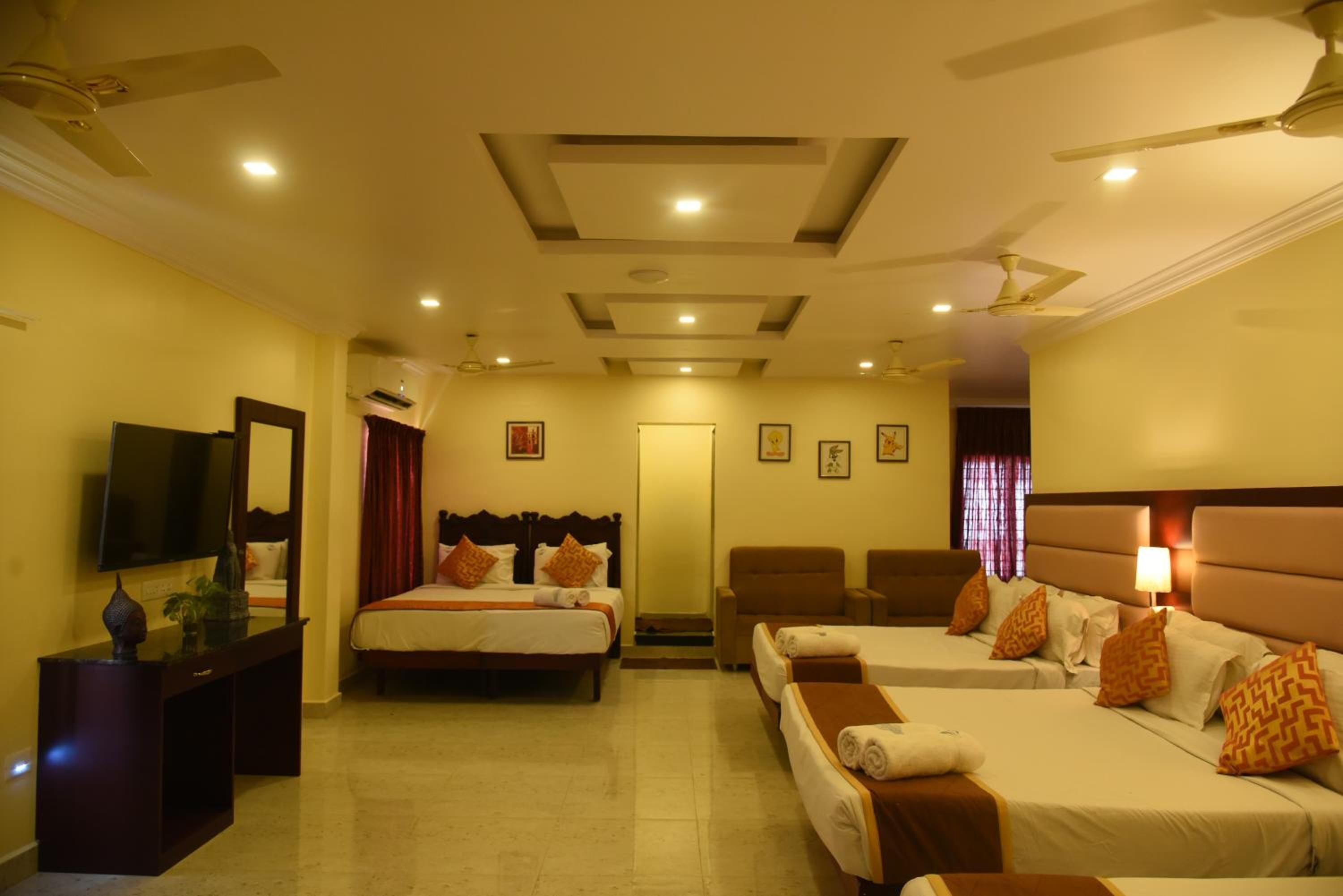 A hotel room with two beds, a TV, a desk, and a ceiling fan.