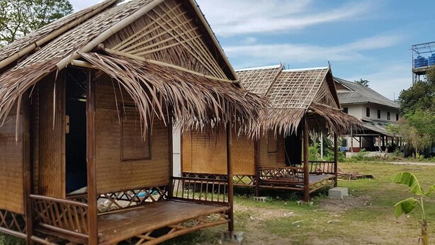 A traditional bamboo hut with a thatched roof, a wooden porch, and a small open doorway. - Lanta Local Hut (Ko Lanta)