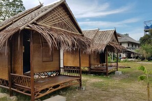 Una cabaña de bambú tradicional con techo de paja, un porche de madera y un pequeño acceso abierto.
