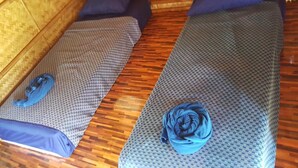 Two single beds with patterned bedding and pillows, a wooden floor, and a woven headboard. - Lanta Local Hut (Ko Lanta)