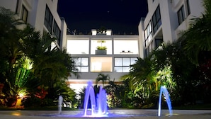 Un edificio moderno con un patio central, rodeado de palmeras y una fuente.