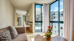 Una sala de estar moderna con un sofá, una zona de comedor y un ventanal con cortinas.