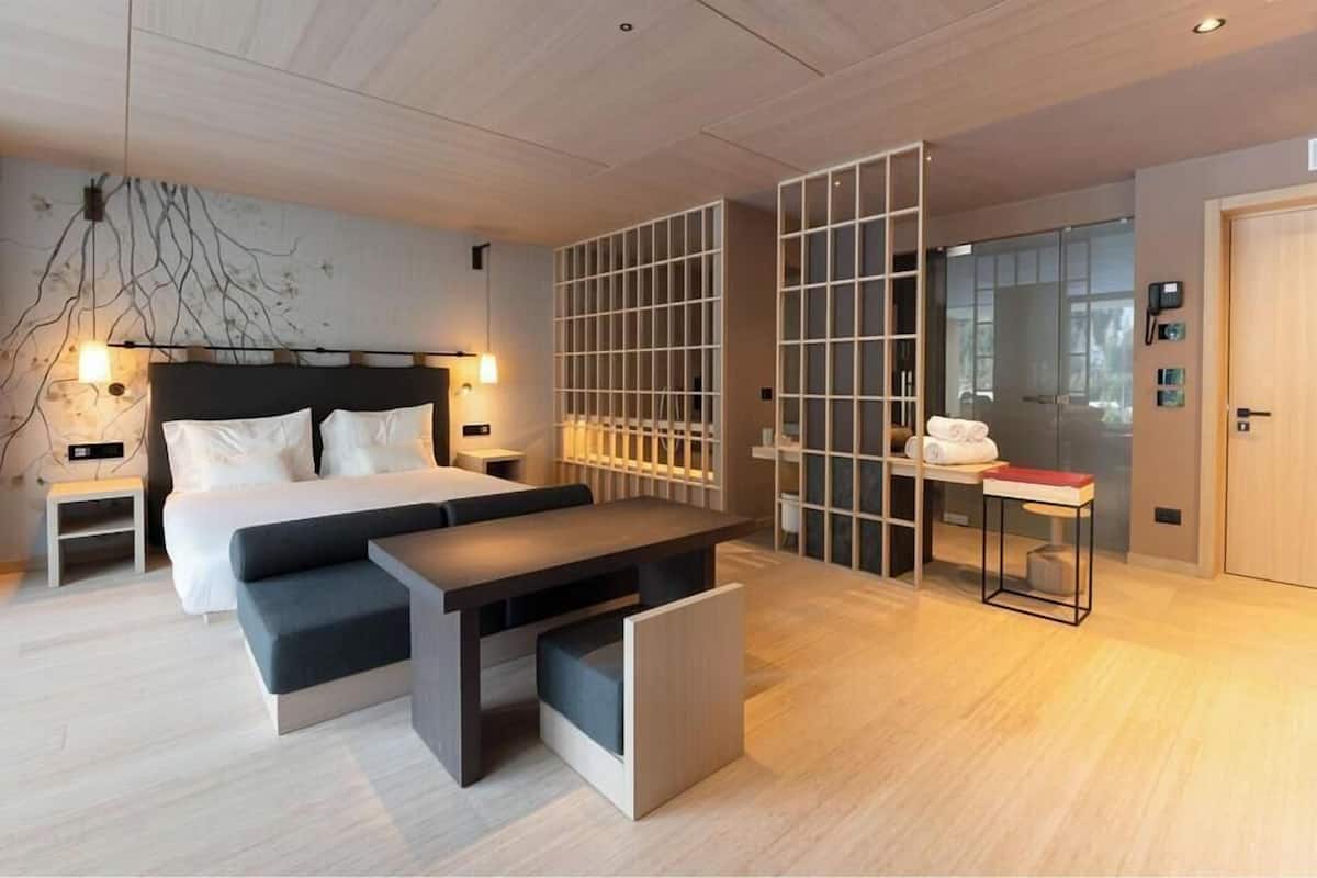 Camera d'hotel moderna con un letto, comodini, una scrivania e una parete divisoria.