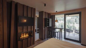 Un dormitorio moderno con chimenea, televisor montado en la pared y balcón con sillas.