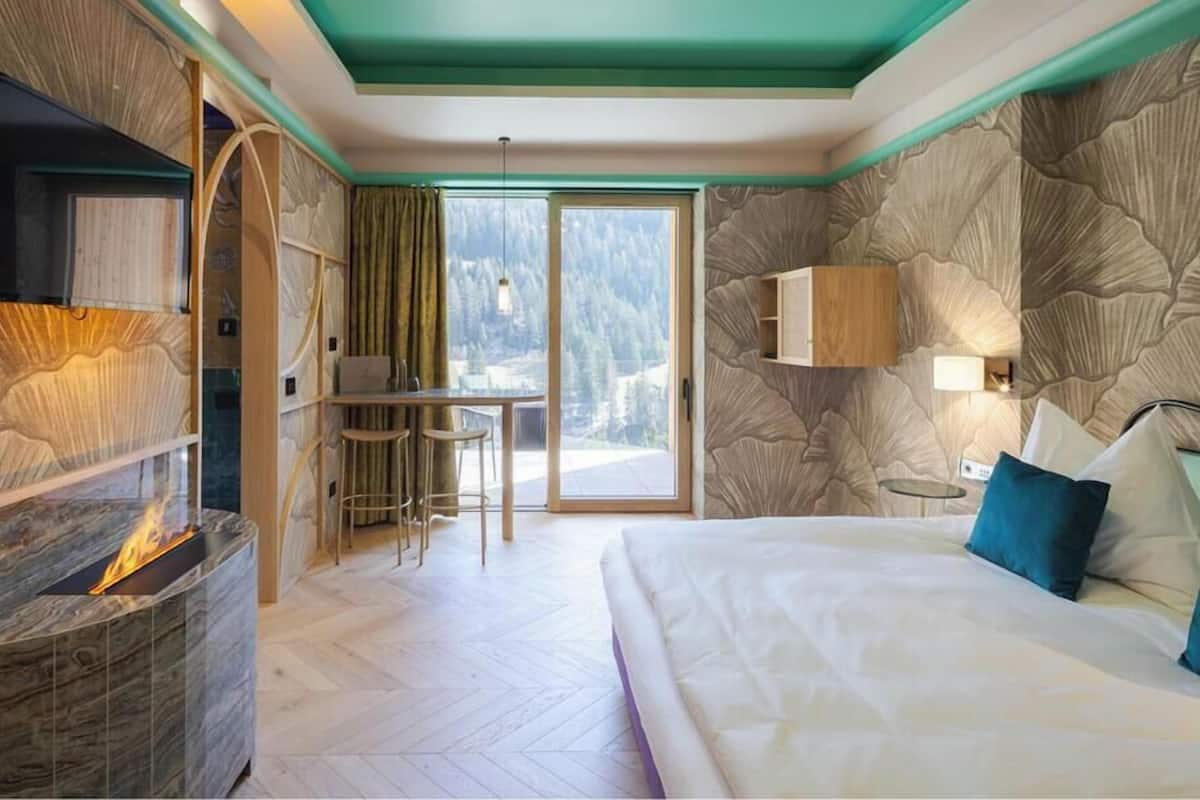 Una camera da letto con un letto grande, un camino, una televisione, un'area pranzo e vista sull'esterno.