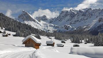 Schneebedeckte Berglandschaft mit Holzhütten und blauem Himmel.