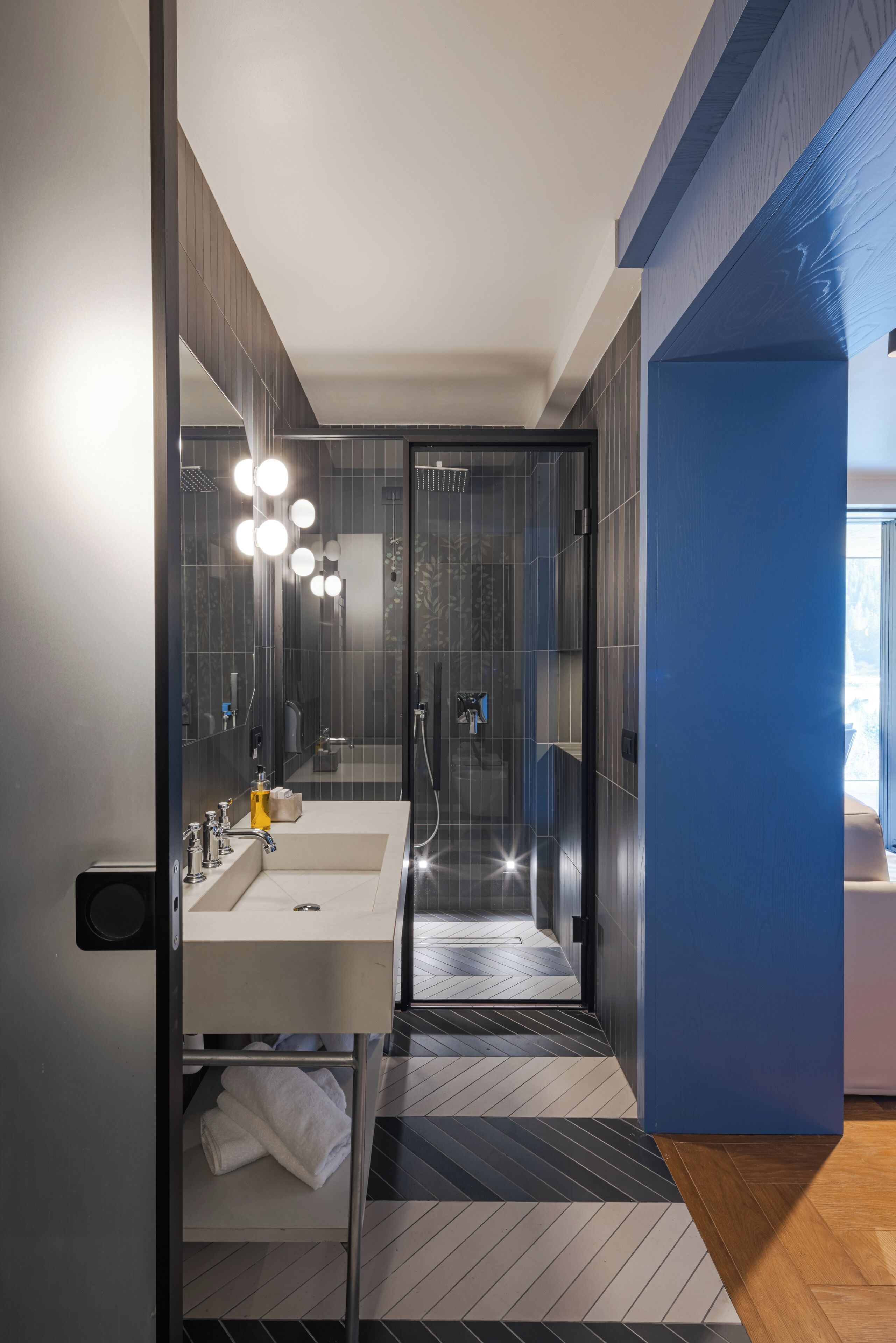 A modern bathroom with a dual sink vanity, a glass shower enclosure, and a visible towel rack.